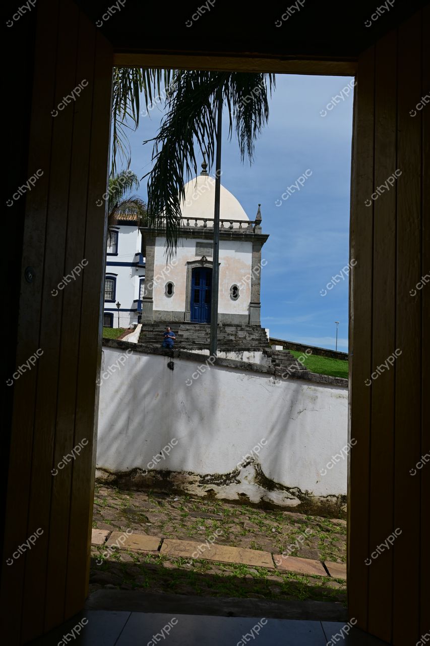 Congonhas, Minas Gerais: Porta de madeira que revela um cenário histórico com cúpula clara e portas azuis