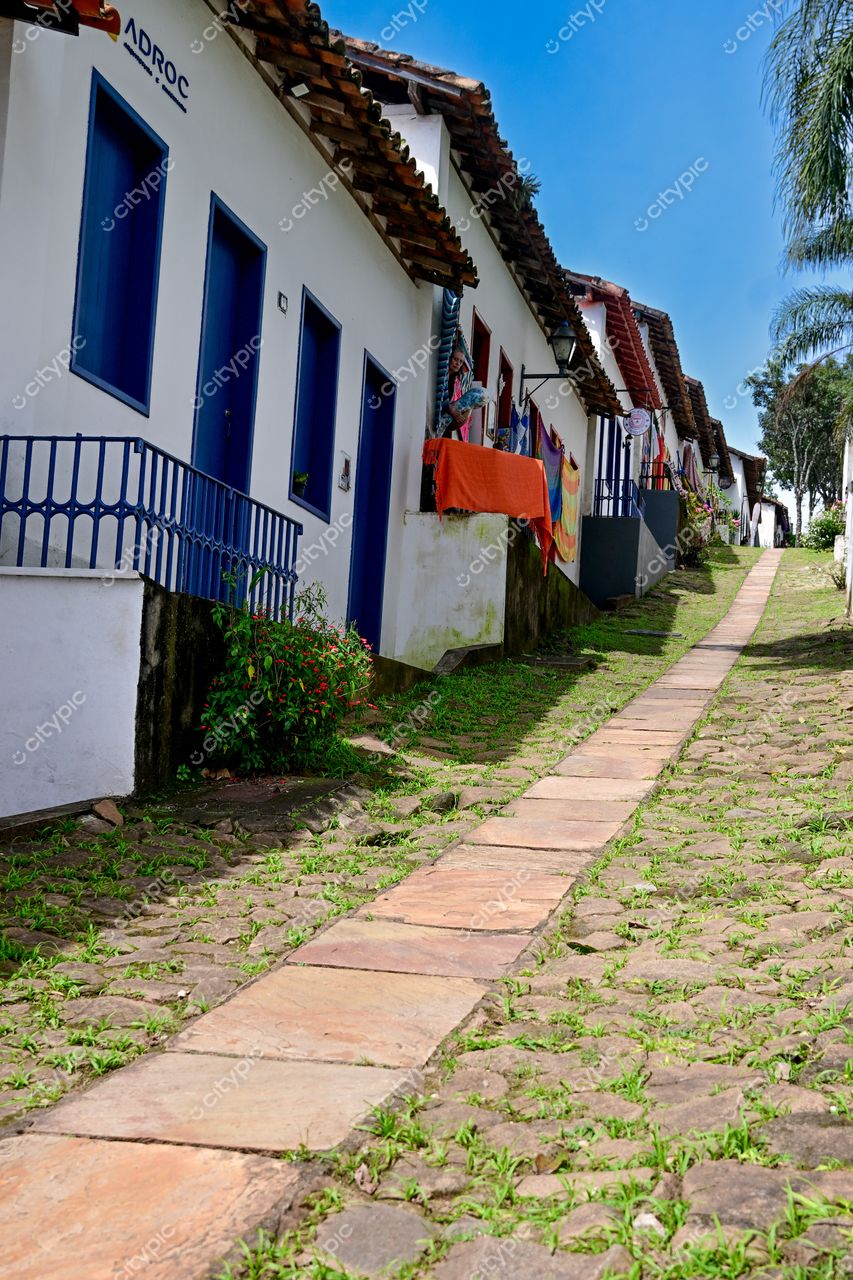 Congonhas, Minas Gerais: Rua encantadora com casas brancas e janelas azuis sob o céu ensolarado