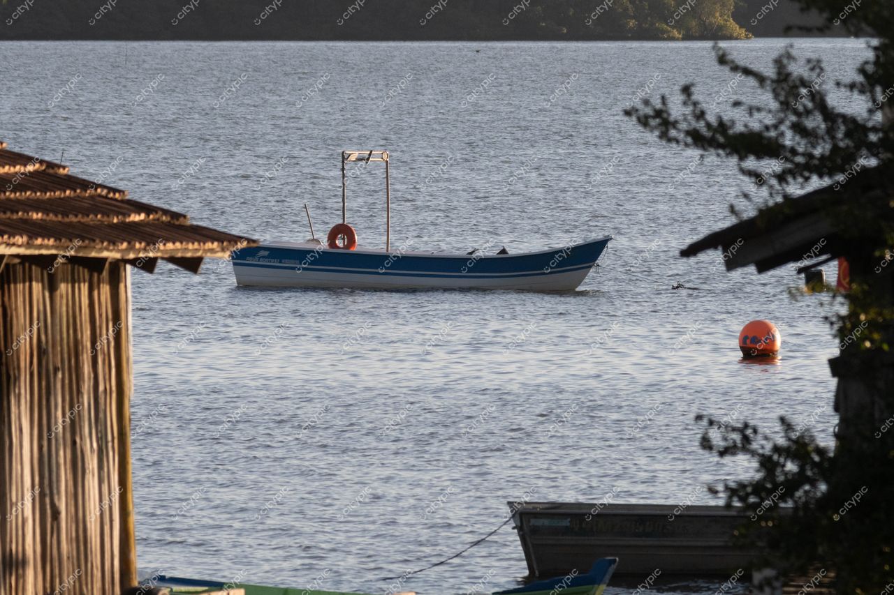 Costeira do Pirajubaé em Florianópolis: Cena tranquila de um barco de pesca e boia laranja