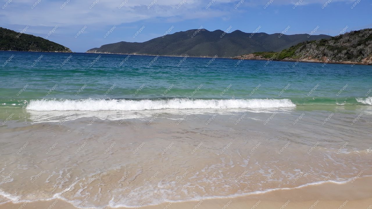 Arraial do Cabo, Rio de Janeiro: Praia paradisíaca com águas cristalinas e montanhas verdes ao fundo