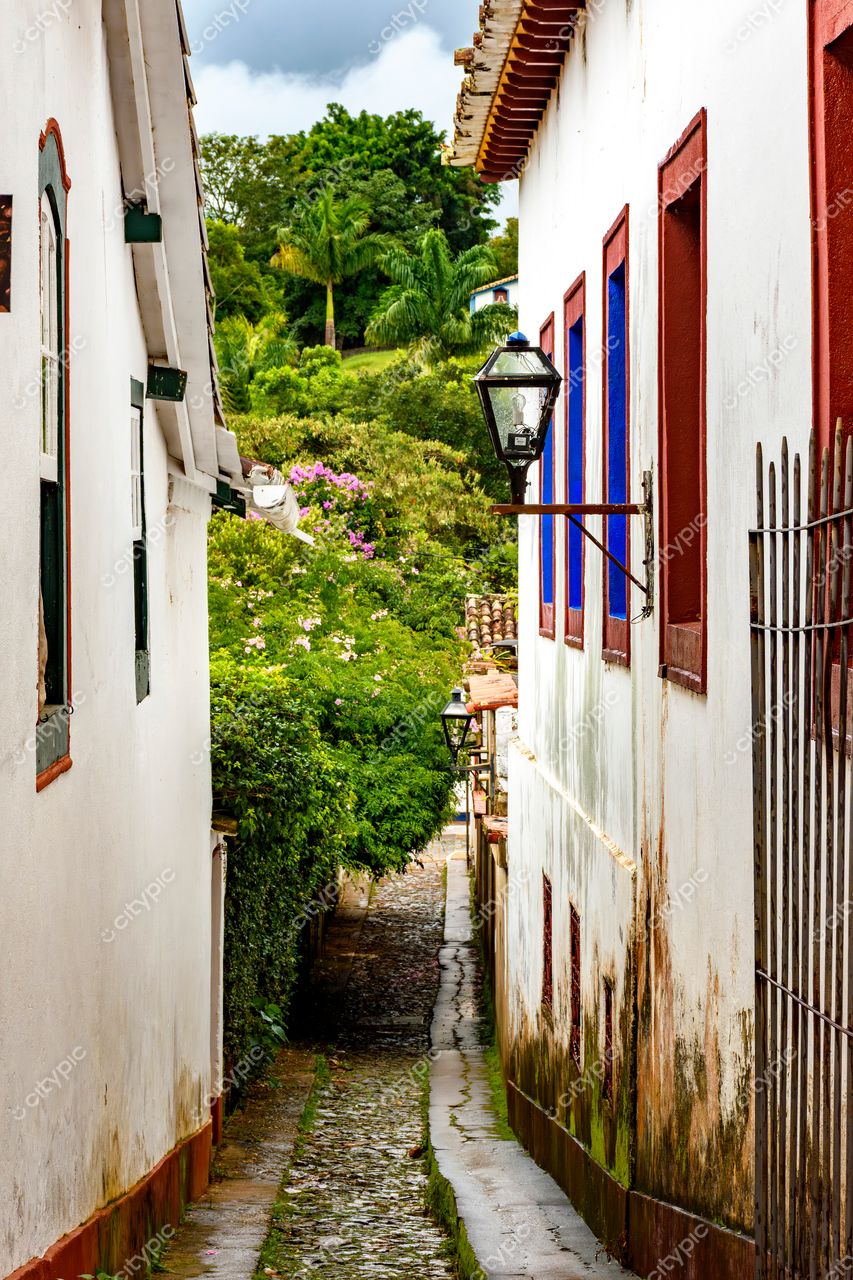 Tiradentes, Minas Gerais: Rua estreita e charmosa com janelas coloridas e vegetação exuberante