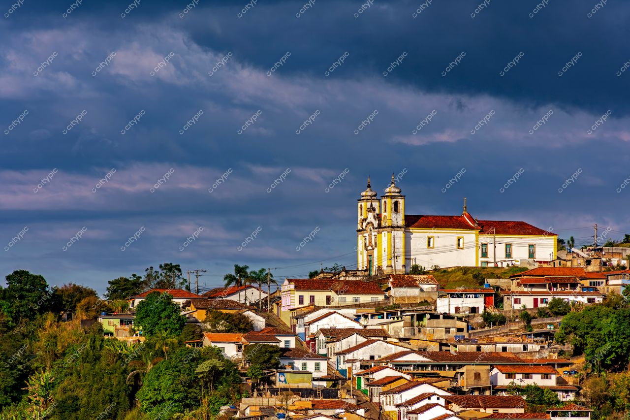 Ouro Preto, Minas Gerais: Vista panorâmica da imponente igreja e casas coloniais em meio à paisagem dramática