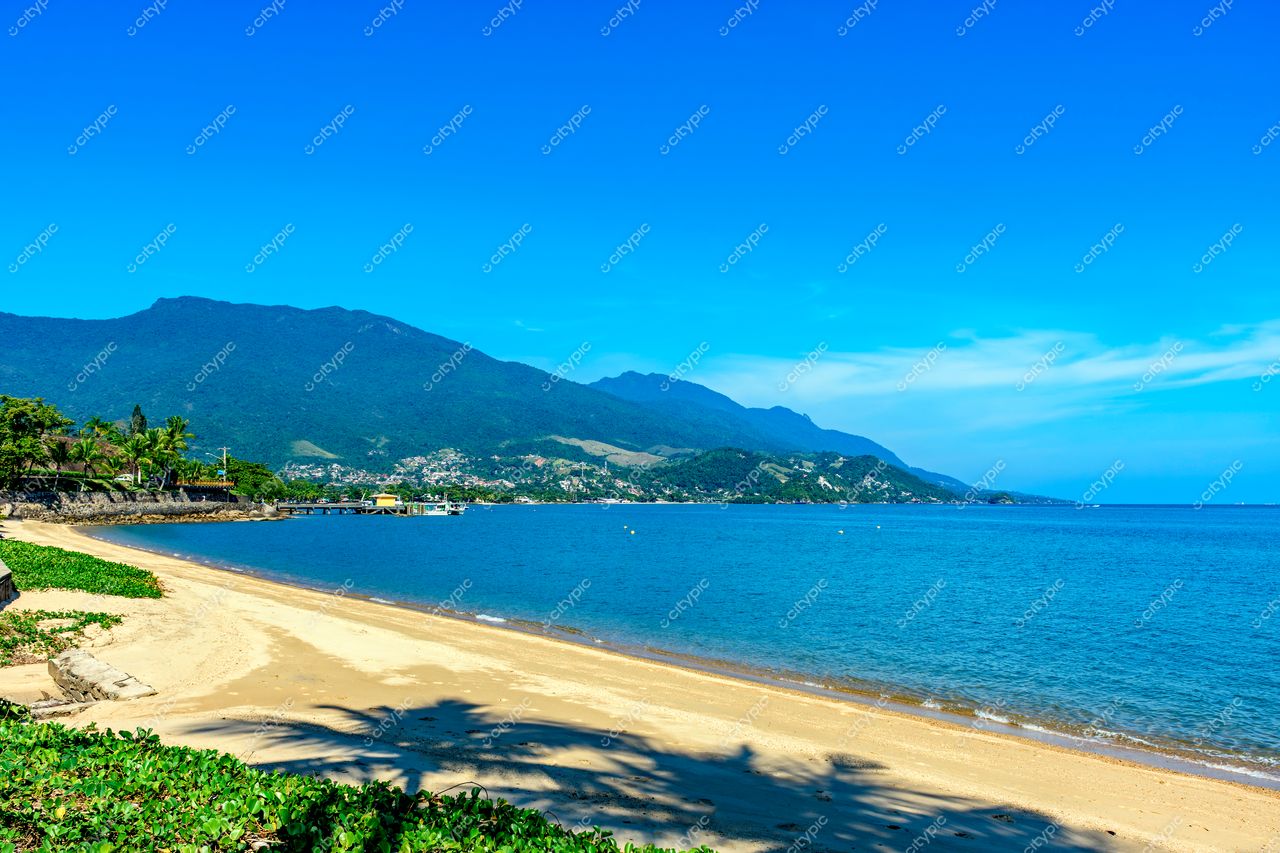 Praia paradisíaca em Ilhabela, São Paulo: águas calmas e transparentes em meio a montanhas verdes e céu azul