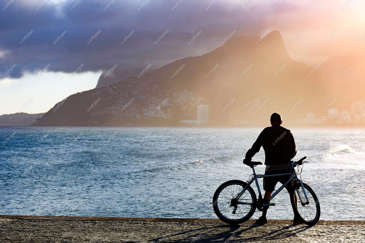 Ciclista contemplando o pôr do sol em Ipanema, Rio de Janeiro, Brasil