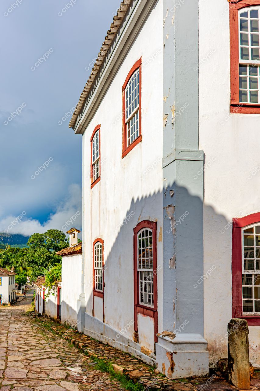 Tiradentes, Minas Gerais: Rua de paralelepípedo com casas coloniais e edifício branco em destaque