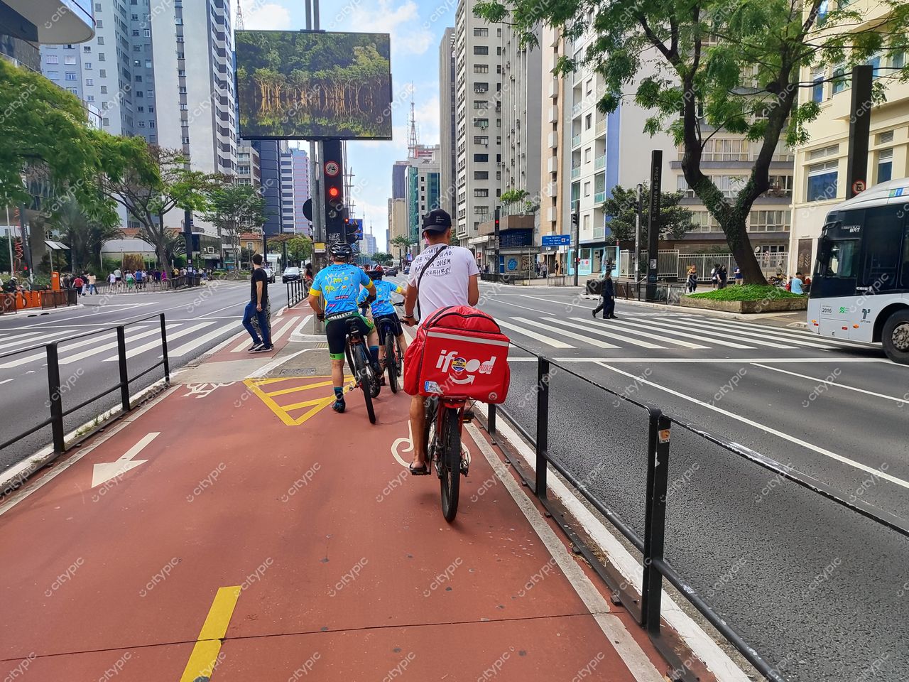 São Paulo, Brasil: Ciclistas e entregador da iFood em movimento na metrópole vibrante