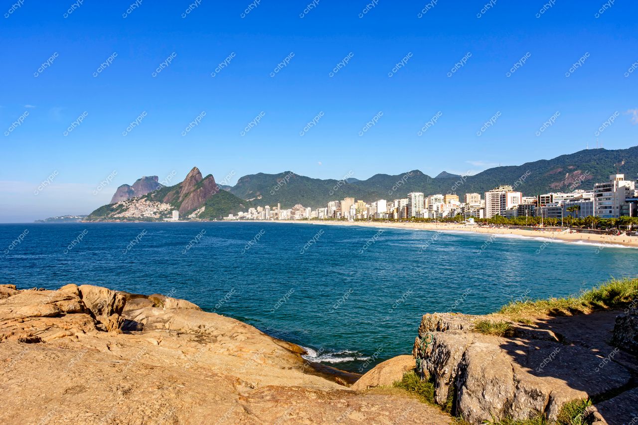 Ipanema, Rio de Janeiro: Vista panorâmica da praia com rochas à beira-mar e paisagem urbana ao fundo