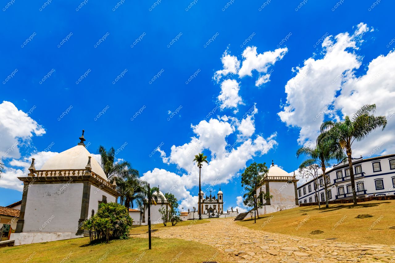 Congonhas, Minas Gerais: Rua de pedras entre edifícios históricos sob um céu azul vibrante