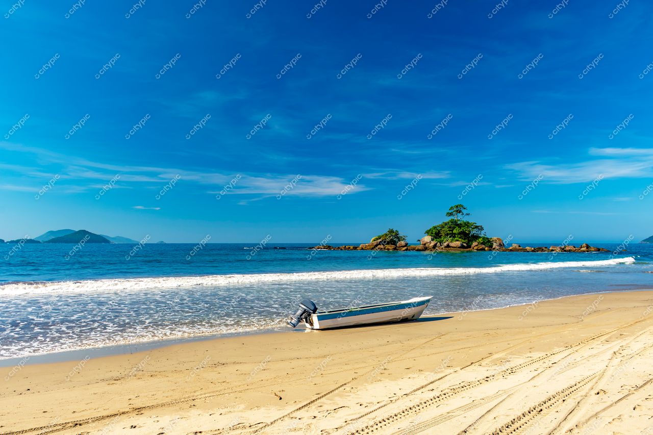 Praia da Tranquilidade em Ilhabela, São Paulo: Lancha ancorada na areia fina e mar calmo refletindo o céu azul sereno