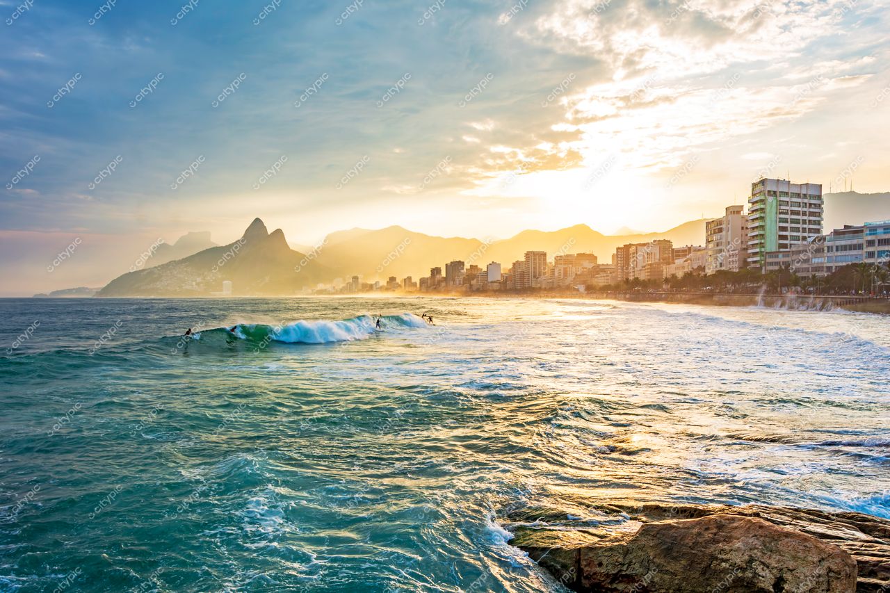 Ipanema ao Amanhecer: Surfistas e a Montanha Dois Irmãos sob um Céu Dramático no Rio de Janeiro, Brasil