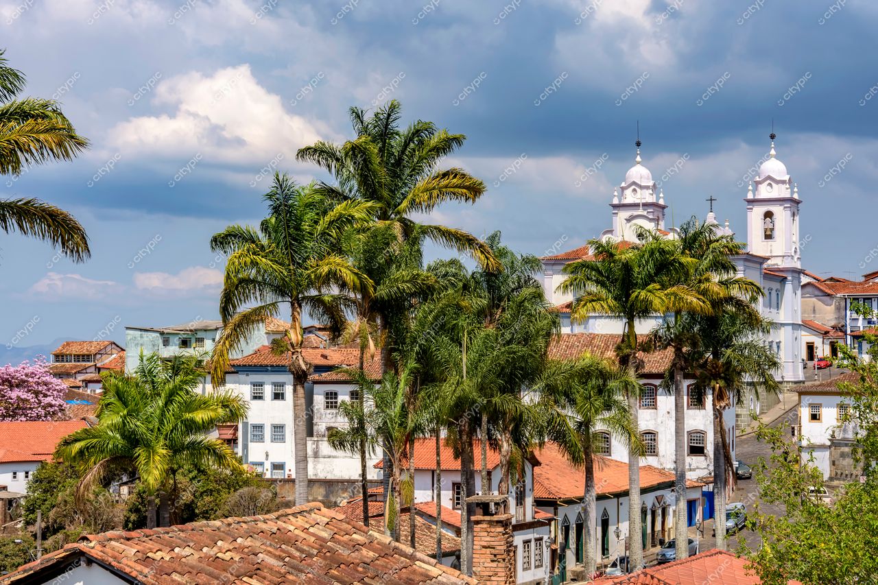 Diamantina, Minas Gerais: Vista panorâmica da cidade histórica com palmeiras exuberantes e igreja ao fundo
