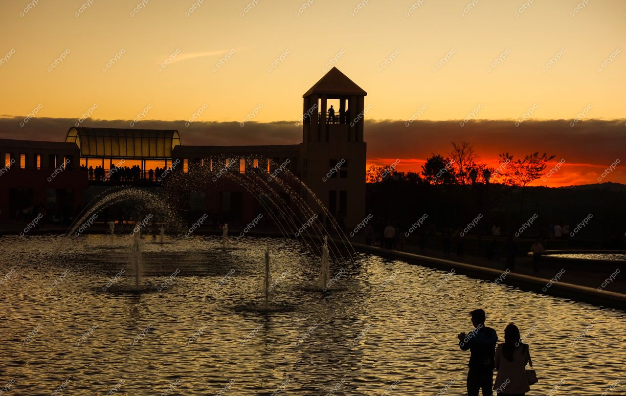 Curitiba, Paraná: Pôr do sol sereno com fonte d’água e silhuetas ao redor