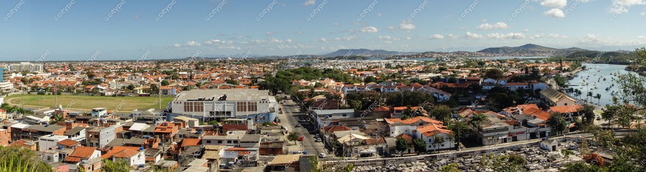 Panorama de Cabo Frio: Vista expansiva da cidade em um dia claro, com montanhas ao fundo e curso d’água serpenteando pela paisagem