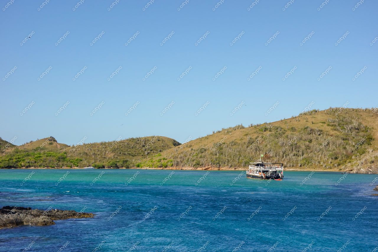 Cabo Frio, Rio de Janeiro: Barco ancorado em águas cristalinas e paisagem serena ao fundo