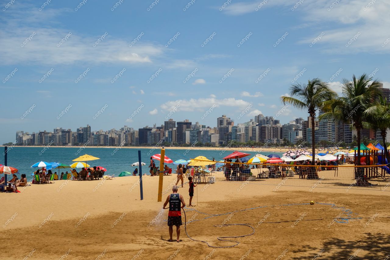 Vila Velha, Espírito Santo, Brasil: Cena vibrante na praia com vôlei de areia e sombrinhas coloridas