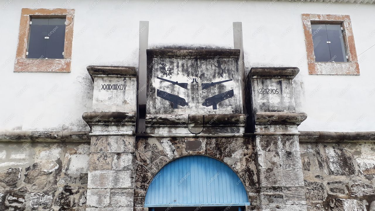 Tamandaré, Pernambuco, fachada antiga de pedra com arco azul e janelas pequenas em ambiente urbano tranquilo e iluminado
