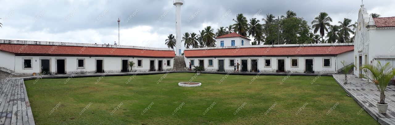 Tamandaré, Pernambuco com gramado central e construções coloniais brancas e telhados vermelhos sob céu nublado