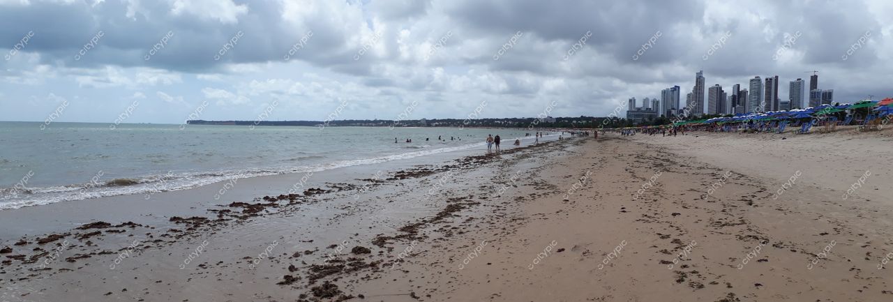 João Pessoa, Paraíba, praia com areia ampla e edifícios altos ao fundo em dia nublado durante a tarde