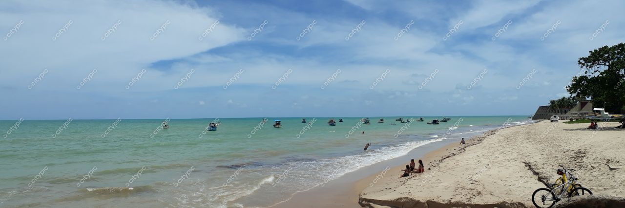 João Pessoa, Paraíba vista panorâmica da praia com mar azul e verde, pessoas na areia e vegetação ao fundo