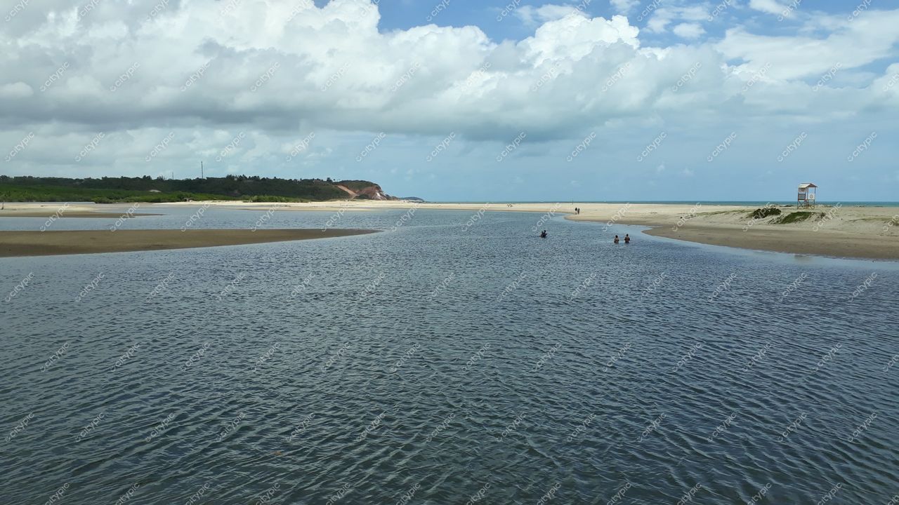 Conde, Paraíba, paisagem tranquila com rio doce, vegetação à esquerda e torre de vigilância ao fundo