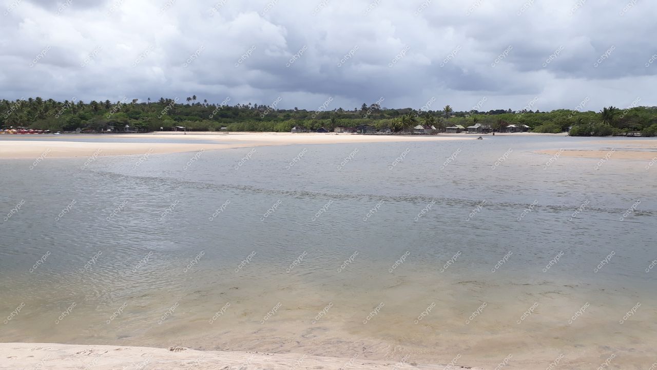 Conde, Paraíba, lago tranquilo com reflexos do céu nublado e vegetação tropical ao redor em dia claro