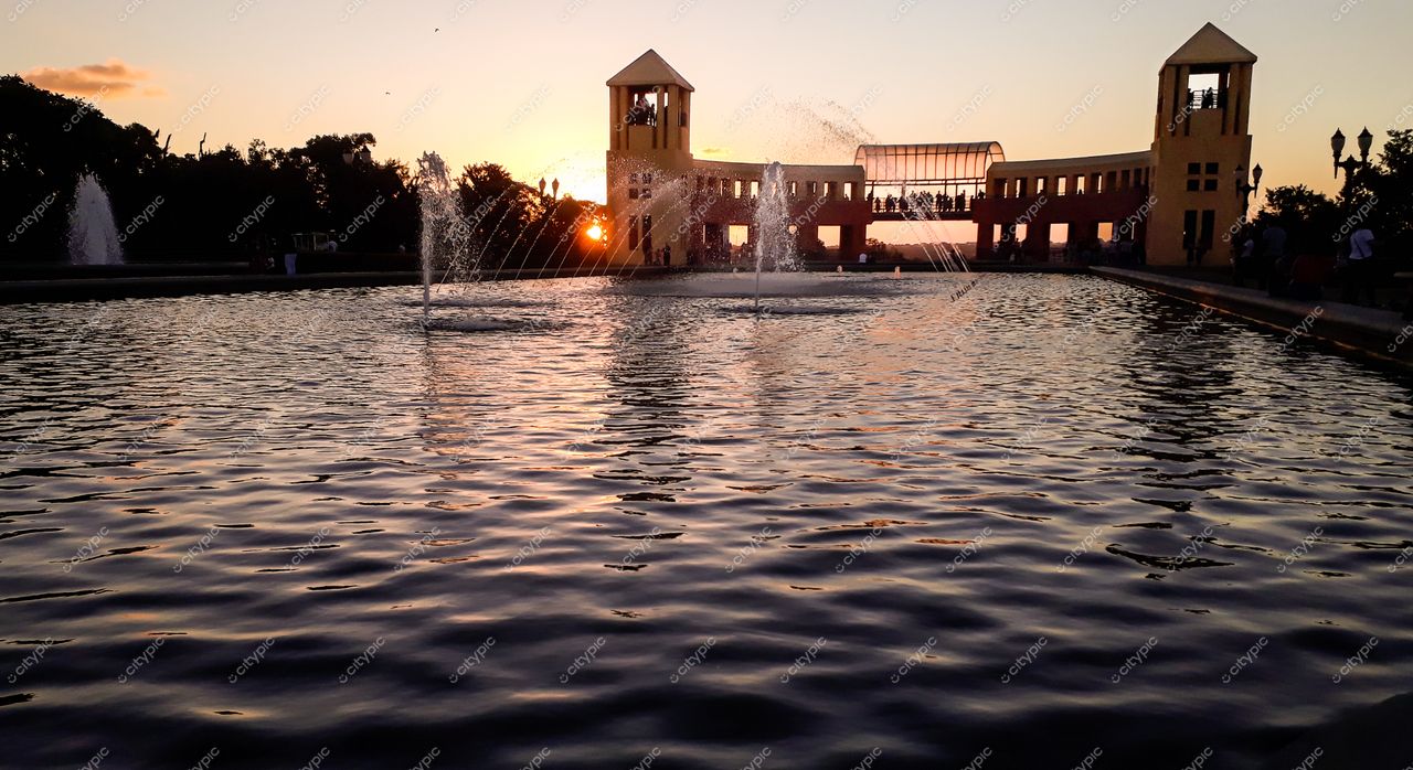 Curitiba, Paraná ao entardecer com reflexo do sol no lago e fontes d’água em destaque na arquitetura urbana