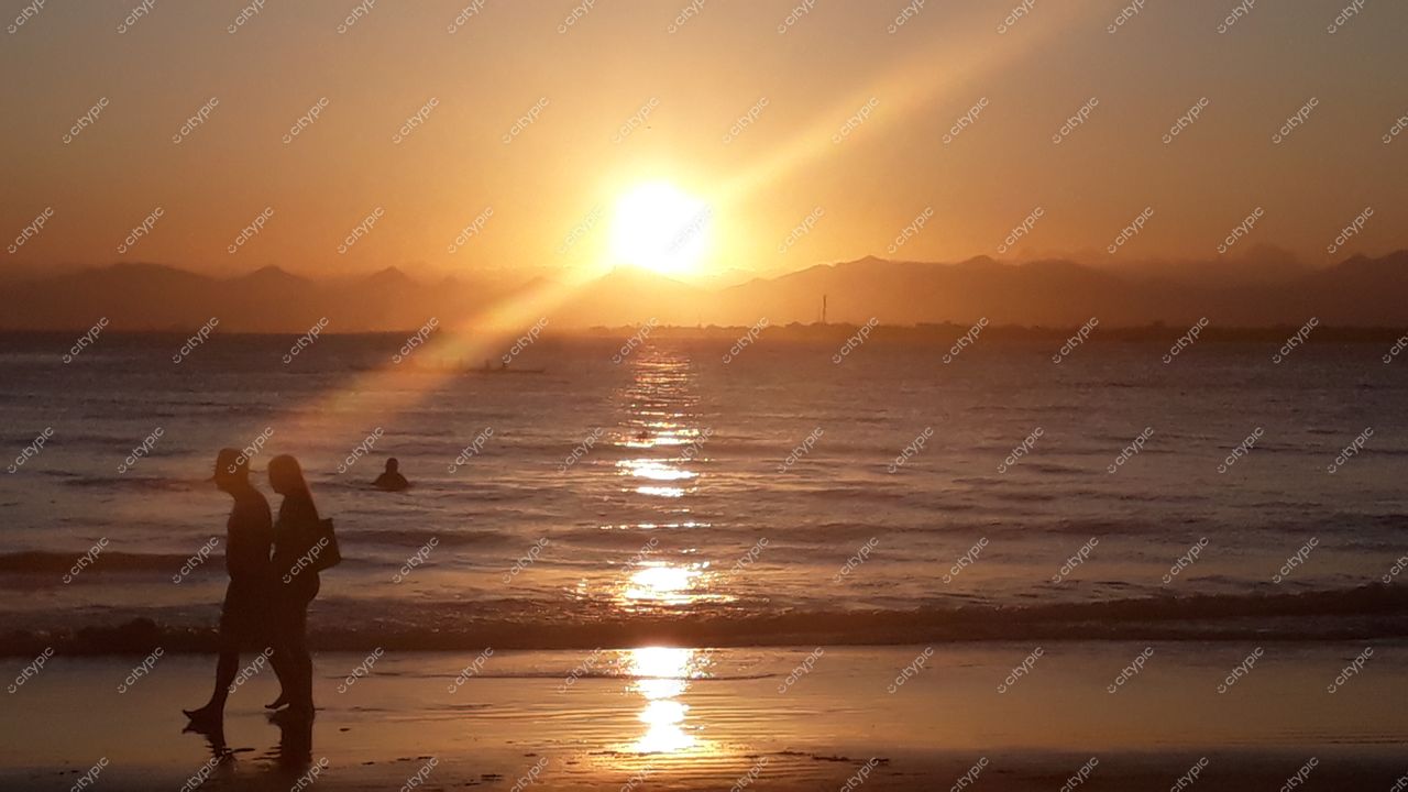 Ilha do Mel Paraná pôr do sol com silhuetas de pessoas na praia e montanhas ao fundo em atmosfera tranquila
