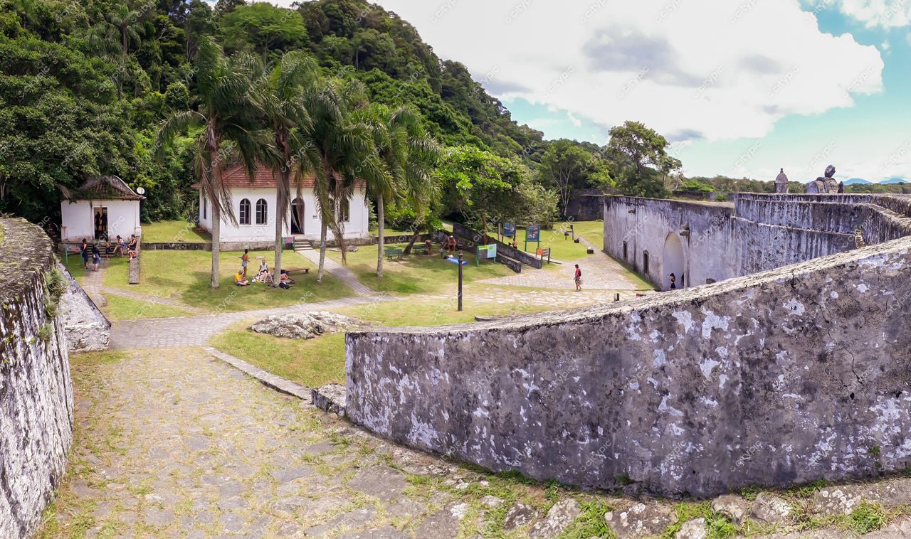 Ilha do Mel, Paraná, arquitetura colonial branca cercada por vegetação exuberante e muros antigos em dia ensolarado