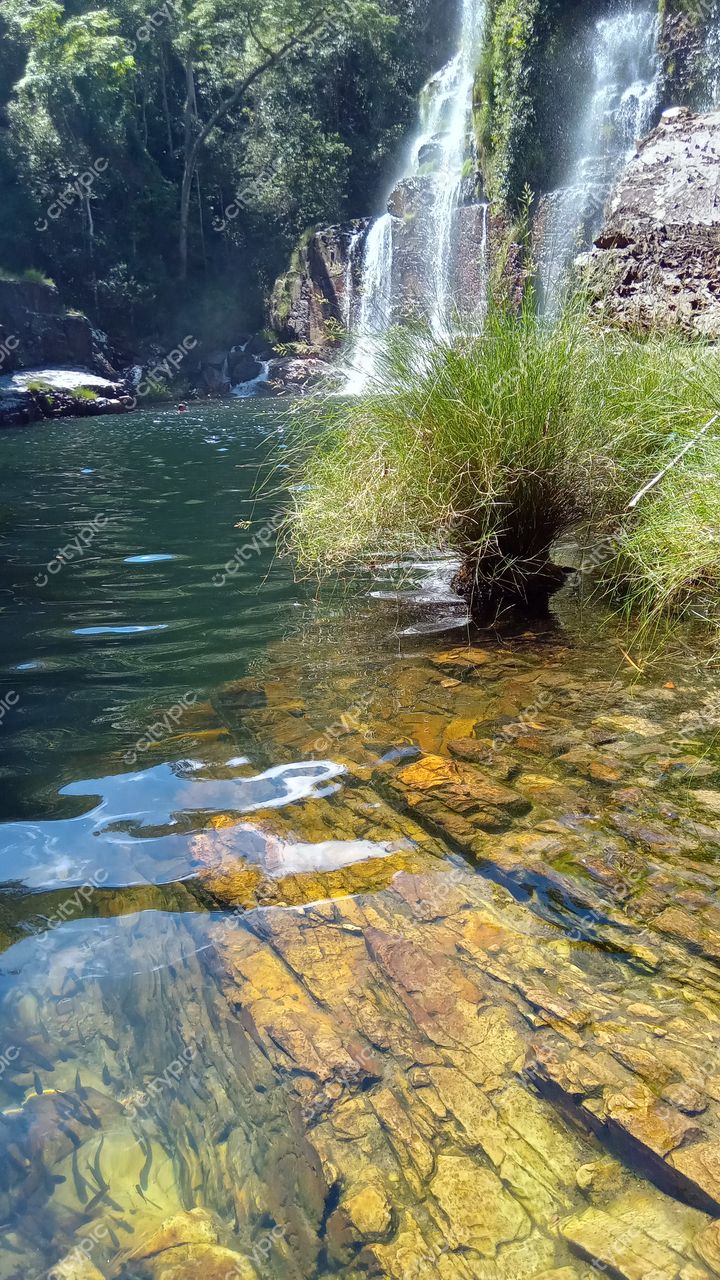 Chapada dos Veadeiros, Goiás, água cristalina refletindo pedras coloridas e vegetação rasteira em dia ensolarado