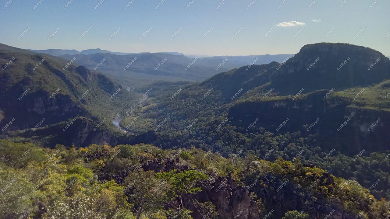 Chapada dos Veadeiros, Goiás vista panorâmica com relevo montanhoso, vegetação densa e rio sinuoso em dia ensolarado