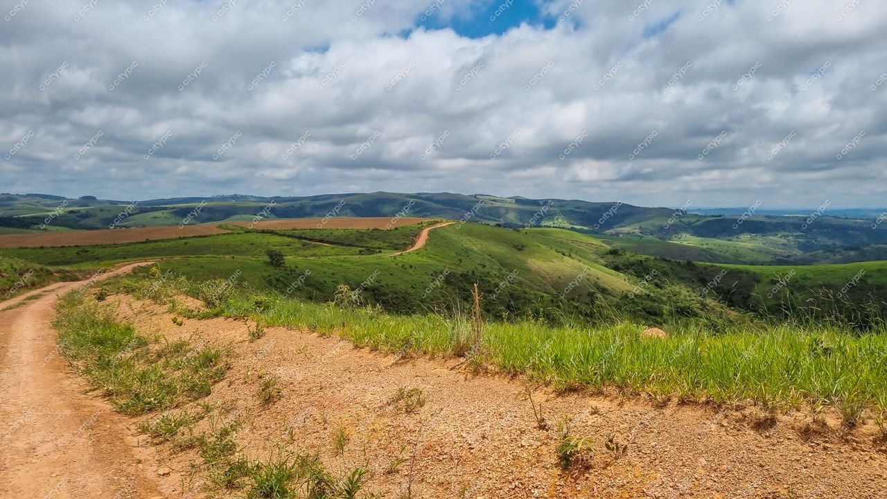 Serra da Canastra, Minas Gerais, colinas verdes e solo árido com caminho de terra em dia claro e nuvens