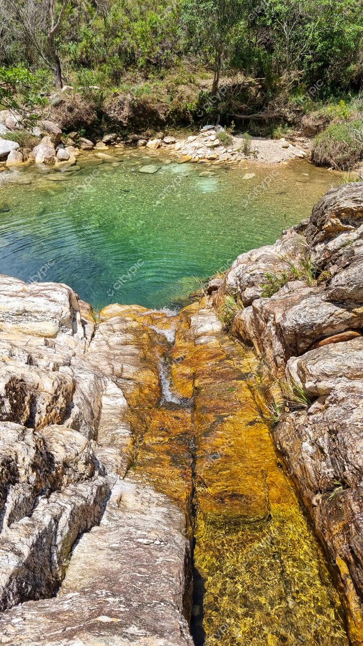 Serra da Canastra, Minas Gerais, poço de água cristalina rodeado por rochas e vegetação em dia ensolarado