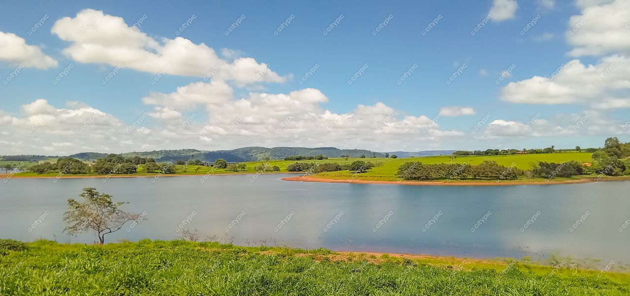Serra da Canastra, Minas Gerais, vista panorâmica de lago calmo refletindo céu azul em dia ensolarado com colinas verdes