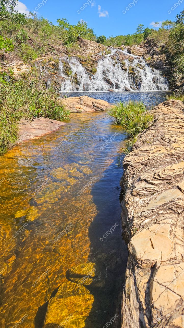 Serra da Canastra, Minas Gerais, cachoeira com água cristalina e vegetação ao redor em dia ensolarado e céu azul claro