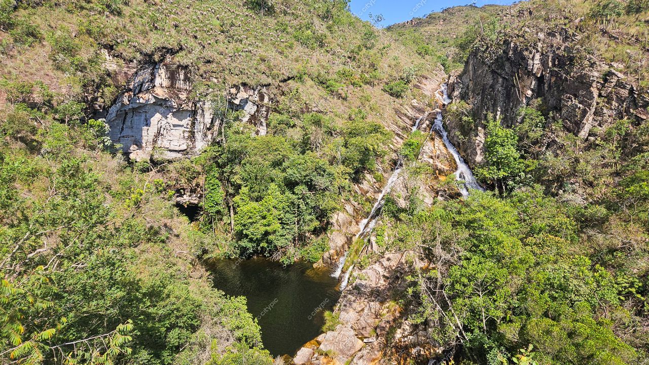 Serra da Canastra, Minas Gerais com vegetação densa e relevo acidentado, cachoeira formando lago em dia ensolarado