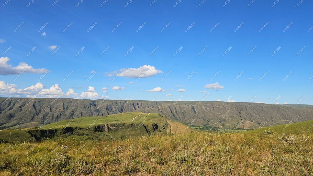 Serra da Canastra, Minas Gerais, dia ensolarado com céu azul e nuvens brancas sobre vegetação verde e relevo montanhoso
