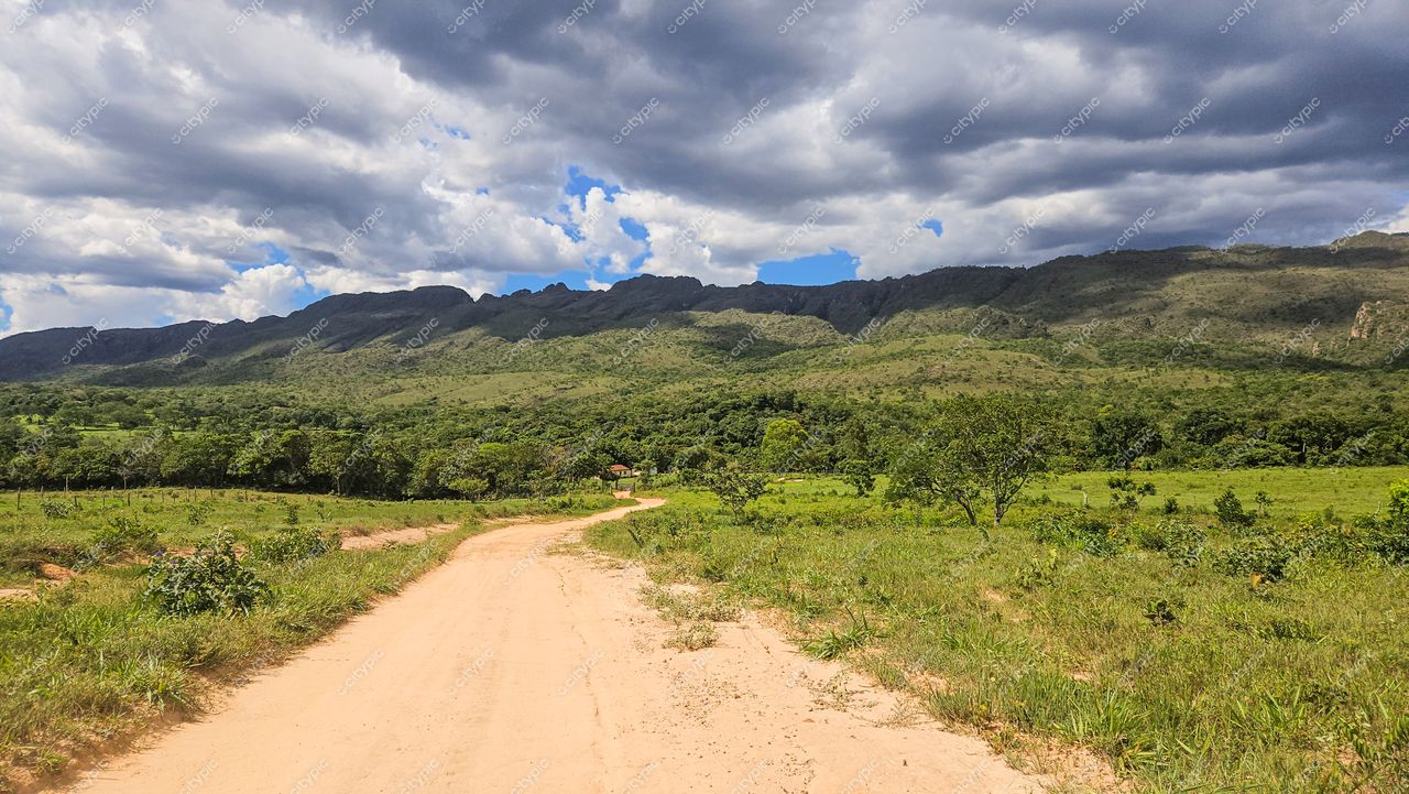 Serra da Canastra, Minas Gerais, estrada de terra serpenteando por paisagem verdejante sob céu parcialmente nublado