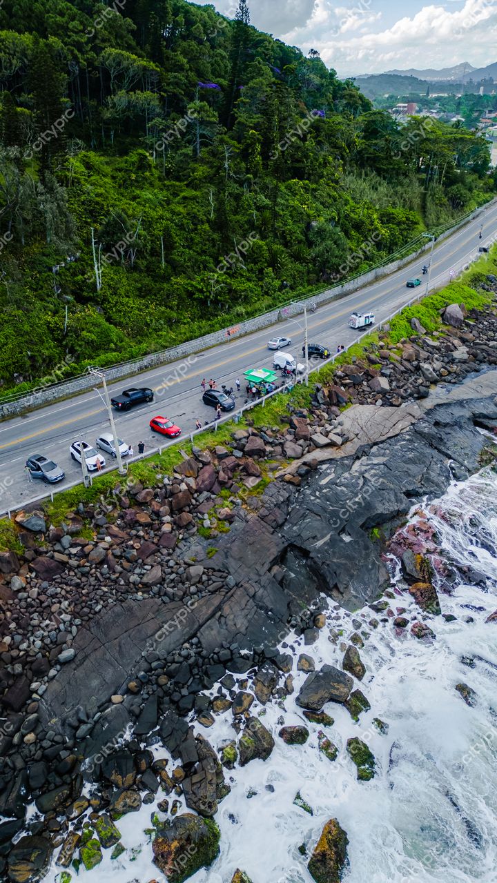 Morro das Pedras e Lagoa do Peri em Florianópolis com vegetação densa e estrada costeira em dia claro