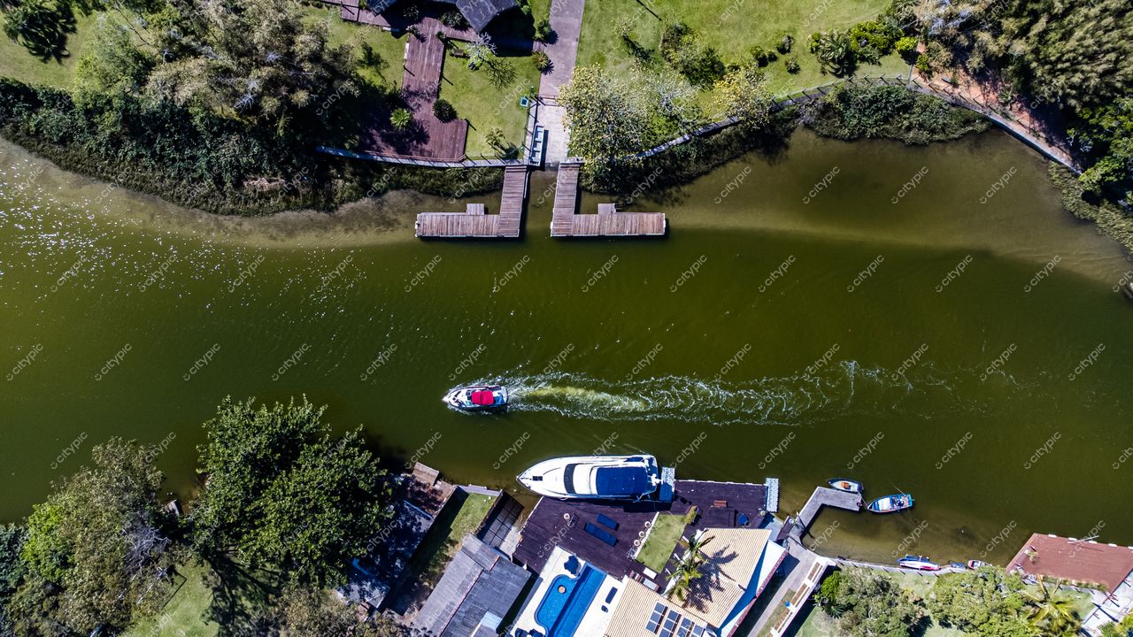 Barra da Lagoa em Florianópolis com canal, barco vermelho e iate branco sob luz do dia e vegetação abundante
