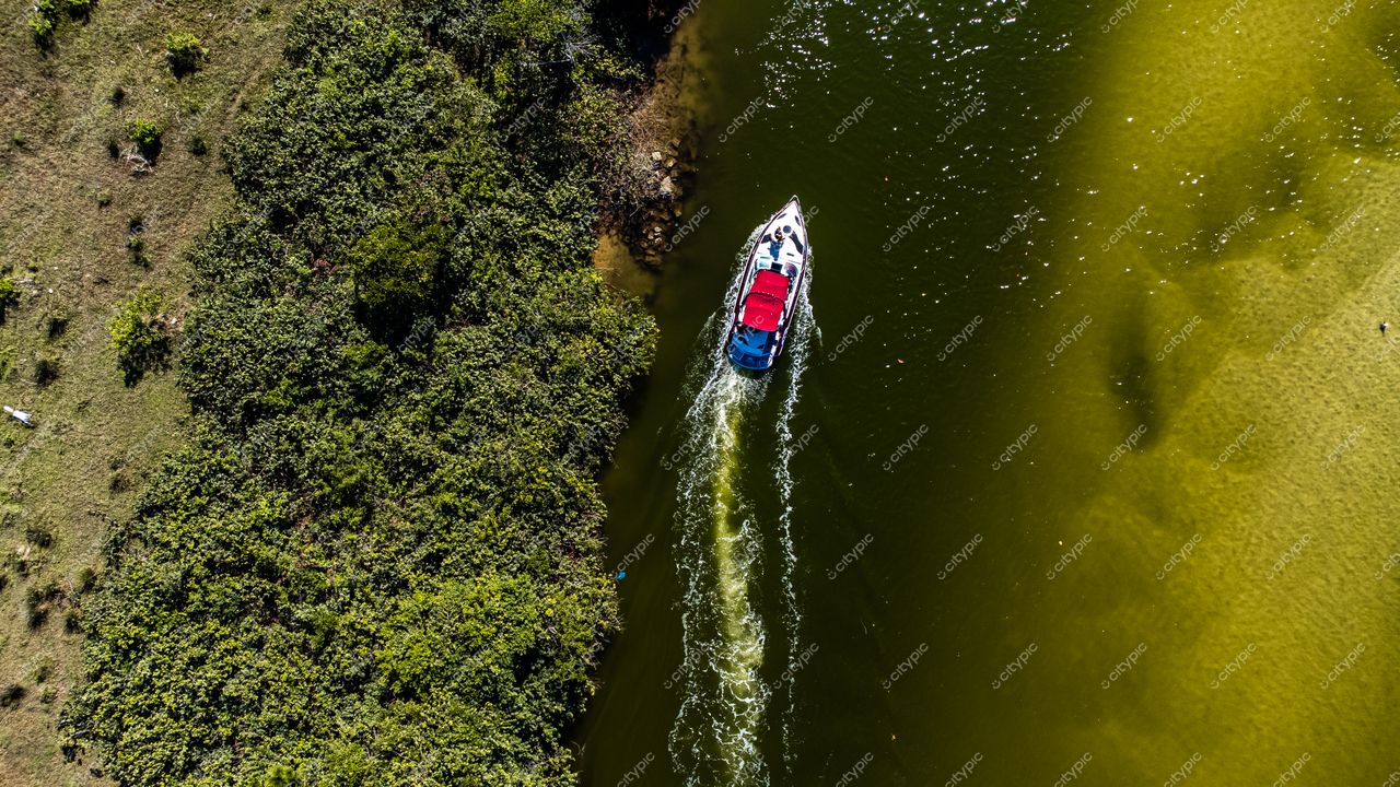 Barra da Lagoa em Florianópolis com lancha vermelha e azul navegando em águas esverdeadas sob sol intenso