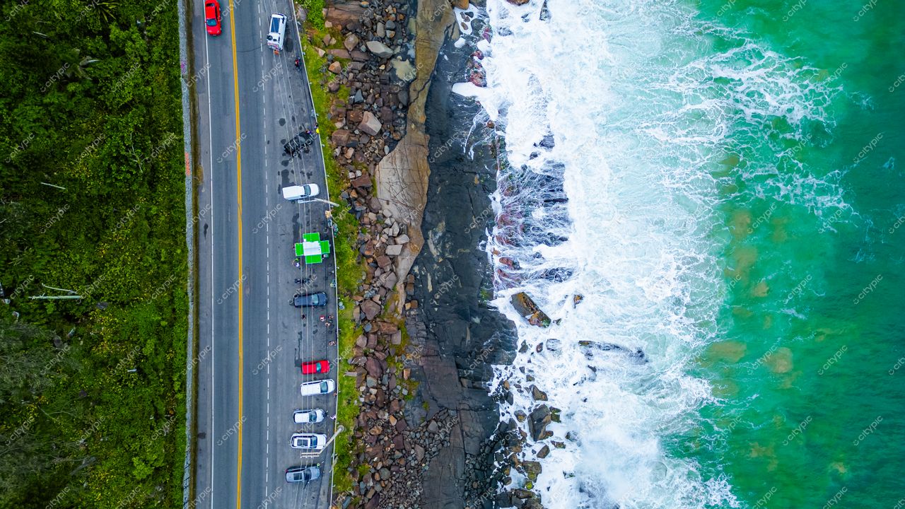 Morro das Pedras e Lagoa do Peri em Florianópolis com estrada contornando a costa e vegetação exuberante à esquerda