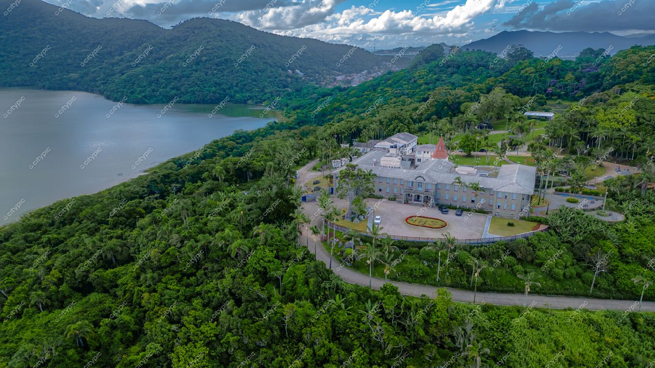 Morro das Pedras e Lagoa do Peri em Florianópolis com edifício de telhado pontudo e vegetação densa ao fundo