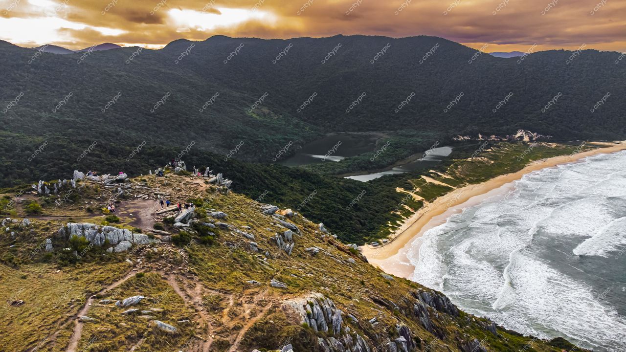 Lagoinha do Leste em Florianópolis com montanhas rochosas, vegetação densa e praia ao entardecer sob céu nublado