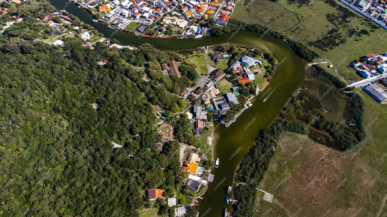 Barra da Lagoa em Florianópolis com vista aérea destacando vegetação densa e residências coloridas em dia claro