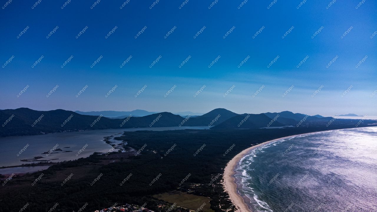 Barra da Lagoa em Florianópolis com litoral de areia clara e águas calmas sob céu azul sem nuvens