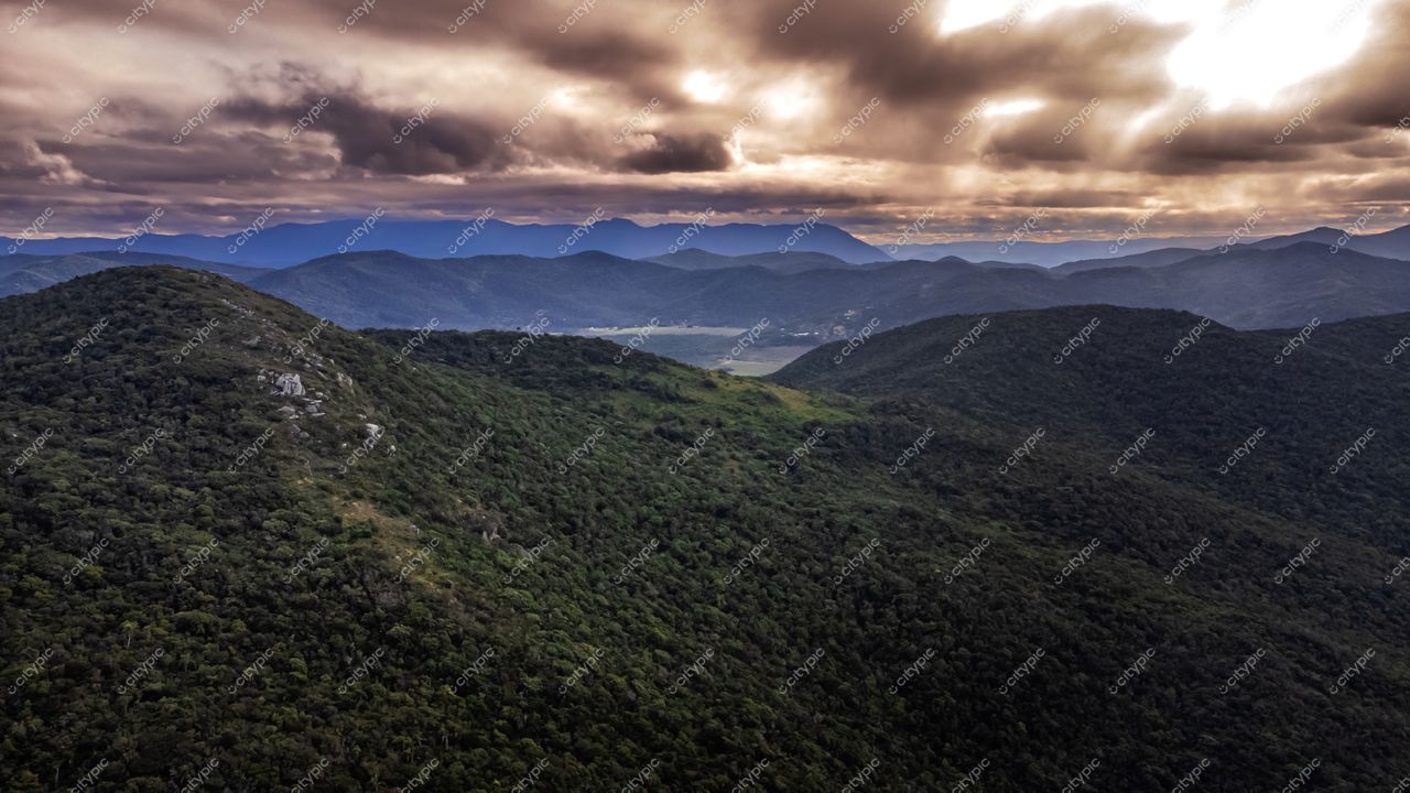 Lagoinha do Leste em Florianópolis com colinas verdes sob céu nublado e iluminação suave ao entardecer
