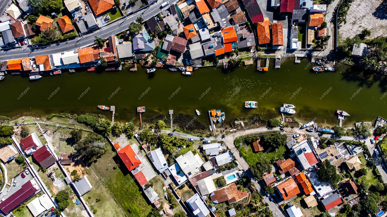 Barra da Lagoa em Florianópolis com casas coloridas, vegetação densa e canal com barcos ancorados durante o dia