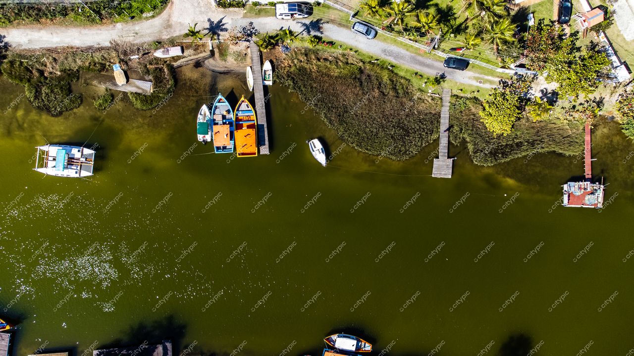 Barra da Lagoa em Florianópolis com canal estreito, embarcações ancoradas e vegetação nativa ao fundo durante o dia