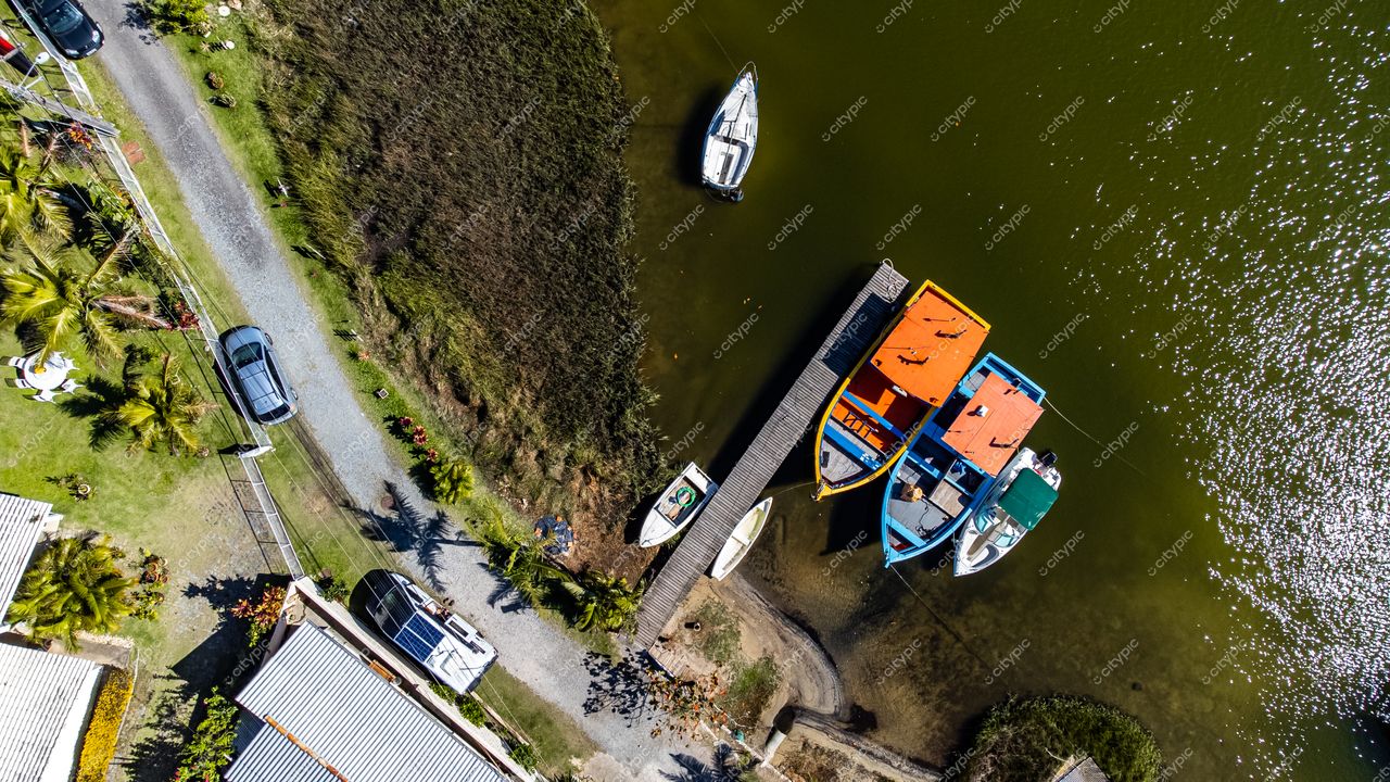 Barra da Lagoa em Florianópolis com cais de madeira, barcos coloridos e vegetação abundante em plena luz do dia