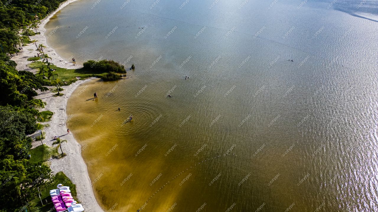 Morro das Pedras e Lagoa do Peri em Florianópolis com águas calmas, vegetação densa e pessoas na areia clara